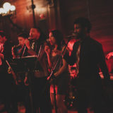 Live jazz band performing in a warm, intimate venue with passionate vocalists and musicians.