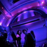 Live band performing under vibrant purple and blue lights at an elegant indoor venue.
