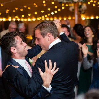Two grooms dancing joyfully at Newagen Seaside Inn wedding in Southport, Maine.