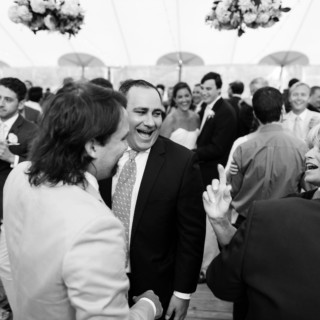 Joyful black-and-white wedding reception at Newagen Seaside Inn with laughing guests and happy newlyweds.