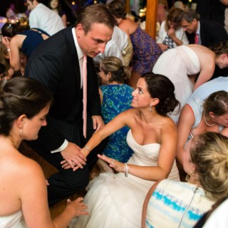 Bride surrounded by guests sharing joyful moment on dance floor at Newagen Seaside Inn wedding.