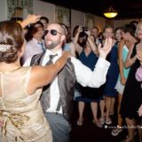 Bearded man and woman in gold dress dancing at joyful Block Island wedding reception.