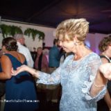 Woman dancing joyfully in light blue lace dress at Block Island wedding reception.