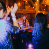 Guitarist performing live at rustic barn wedding in Lloyd Neck, NY under warm string lights.