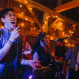 Live wedding band performing in rustic barn with warm lights and joyful energy