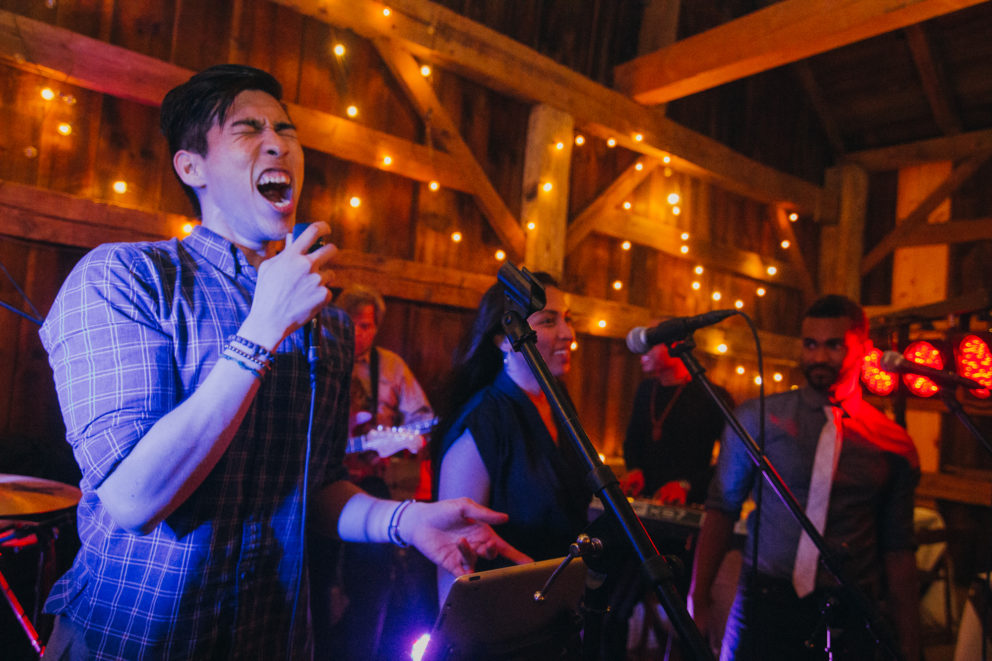 Live wedding band performing in rustic barn with warm lights and joyful energy