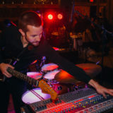 Guitarist adjusting sound mixer during live performance at rustic wedding venue in Lloyd Neck, NY.