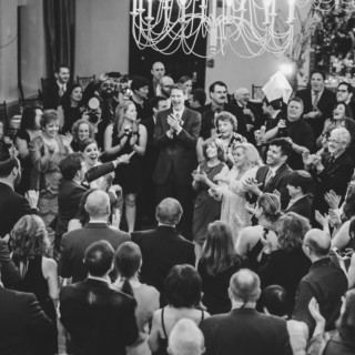 Black and white wedding celebration at Alden Castle with guests dancing and clapping in joy.