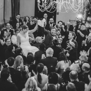 Bride and groom lifted on chairs during joyful hora dance at Alden Castle wedding.