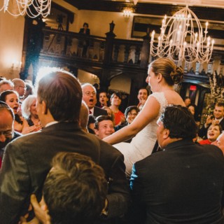 Bride lifted on chair during joyful Jewish wedding celebration at Alden Castle, Brookline MA.