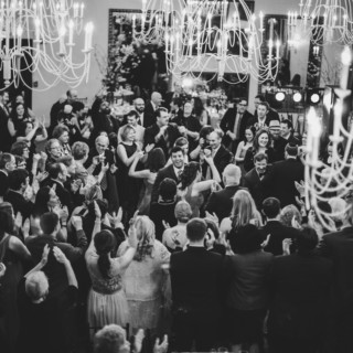 Elegant black-and-white wedding celebration at Alden Castle in Brookline with joyful guests and chandeliers.