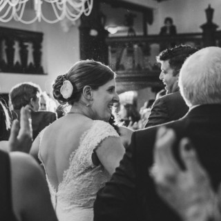 Smiling bride in lace gown surrounded by joyful guests at elegant Alden Castle wedding reception.