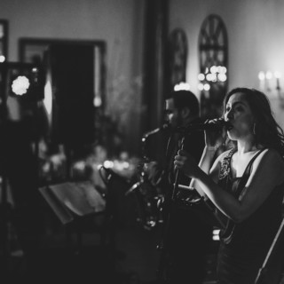 Black and white photo of a soulful singer performing with saxophonist at elegant wedding reception.
