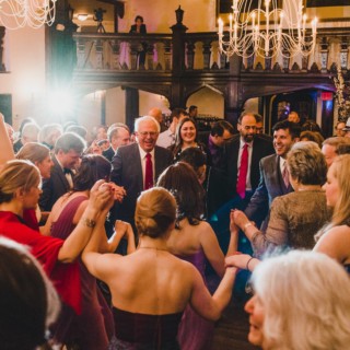 Guests joyfully dancing in a golden-lit wedding celebration at Alden Castle, Brookline MA.