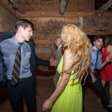Guests dancing joyfully at rustic Vermont barn wedding with warm lights and lively celebration.