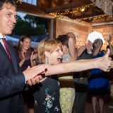 Joyful guests celebrate at a rustic Vermont wedding reception with laughter, cheers, and festive lights.