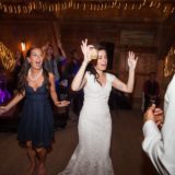 Bride dancing joyfully with guests under string lights at rustic barn wedding in Bristol, Vermont.