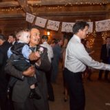 Father dancing with son at rustic barn wedding in Bristol Vermont under glowing string lights.