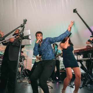 Vibrant live wedding band performing under a white tent in New Hampshire celebration.