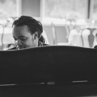 Black and white photo of jazz pianist and saxophonist performing in an intimate lounge setting.