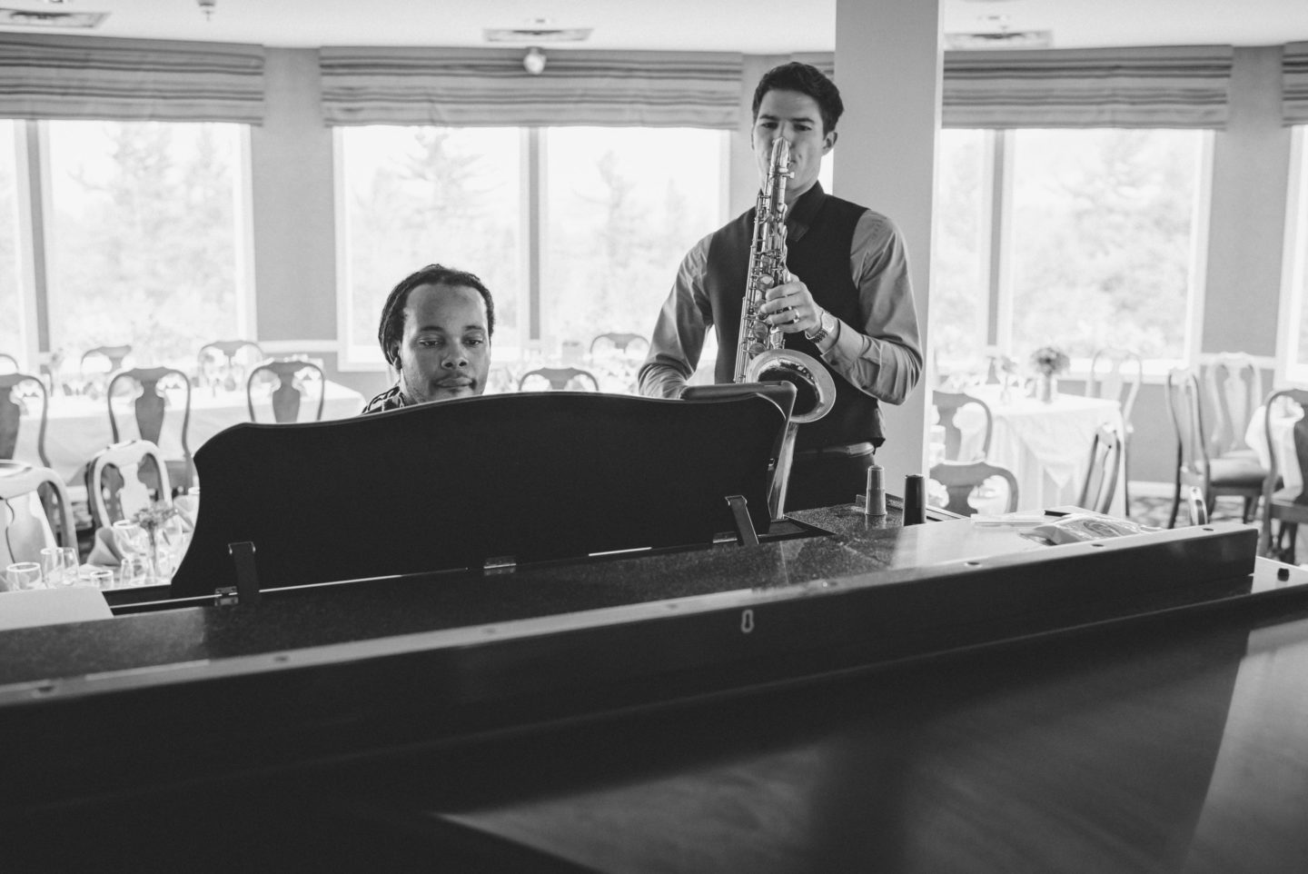 Black and white photo of pianist and saxophonist performing in an elegant hotel lounge.