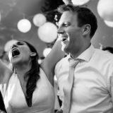 Joyful couple dancing under string lights at a black-and-white wedding celebration in Bar Harbor.