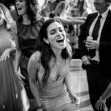 Laughing woman dancing joyfully with friends at elegant Bar Harbor wedding celebration.