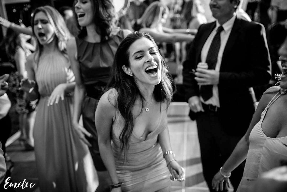 Laughing woman dancing joyfully with friends at elegant Bar Harbor wedding celebration.