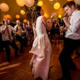 Bride and groom dancing joyfully under warm lights at elegant Bar Harbor wedding reception.