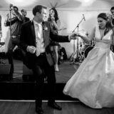Bride and groom dancing joyfully under tent lights at Bar Harbor wedding reception.