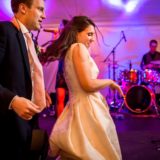 Couple dancing joyfully under colorful lights with live band at Bar Harbor wedding reception.