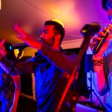 Three singers performing energetically under colorful lights at a lively wedding reception.