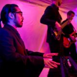 Keyboardist performing live with band under colorful stage lights at Bar Harbor wedding reception.