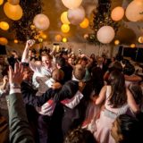 Joyful wedding reception dance floor with guests celebrating under glowing lanterns in Bar Harbor Maine