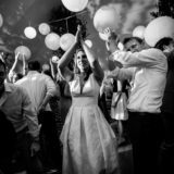 Black and white wedding guests dancing and clapping under glowing lanterns in Bar Harbor.