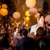 Bride lifted during joyful Hora dance under glowing lanterns at coastal Maine wedding celebration.