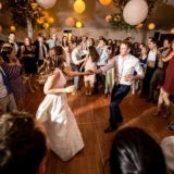 Bride and groom dancing joyfully at Bar Harbor wedding surrounded by cheering guests.