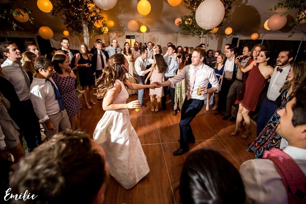 Bride and groom dancing joyfully at Bar Harbor wedding surrounded by cheering guests.
