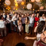 Guests dancing and celebrating under glowing lanterns at a joyful Bar Harbor wedding reception.