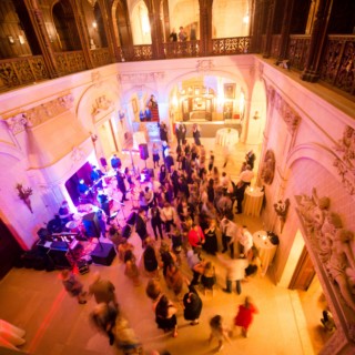 Guests dancing under golden and magenta lights in the grand ballroom of Ochre Court Newport.