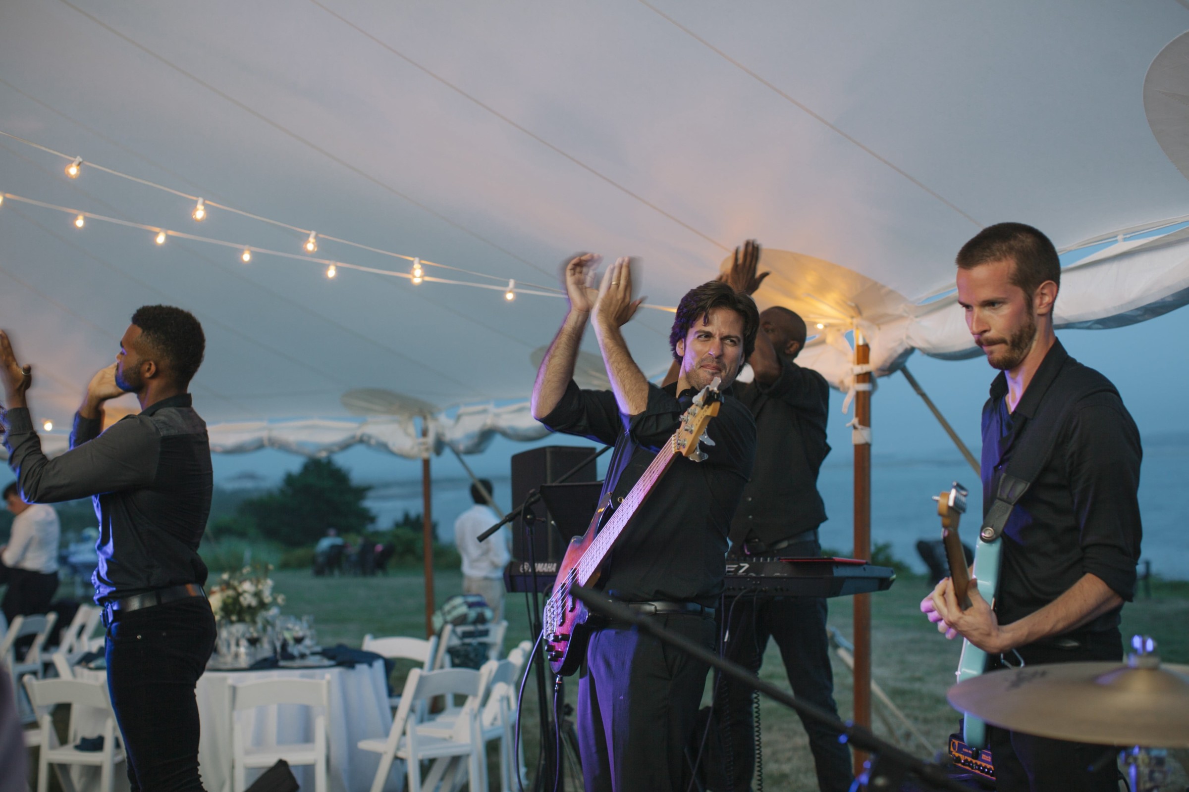 Live band performing under string lights at elegant waterfront wedding on Cuttyhunk Island.