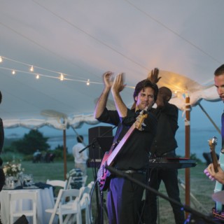 Live band performing under string lights at elegant waterfront wedding on Cuttyhunk Island.