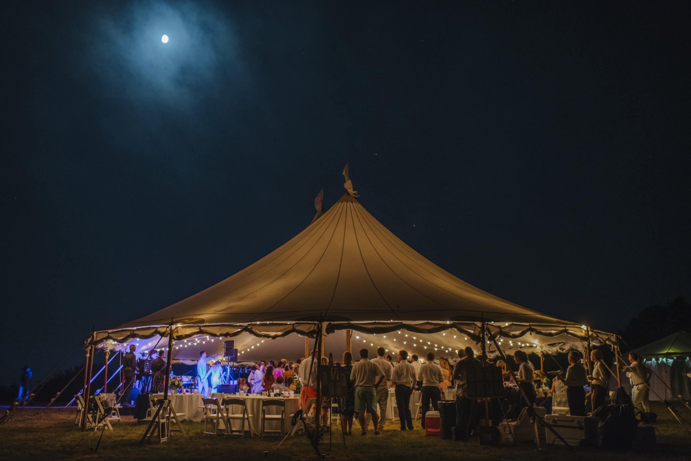 Elegant outdoor wedding reception under glowing string lights on Cuttyhunk Island at night.