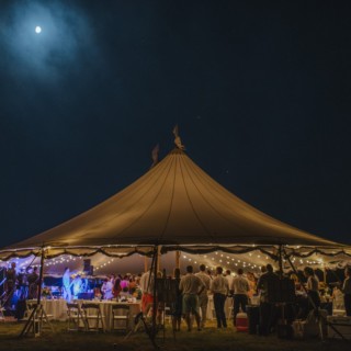 Elegant outdoor wedding reception under glowing string lights on Cuttyhunk Island at night.