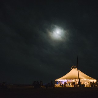 Moonlit wedding tent glowing on Cuttyhunk Island under a starry coastal night sky.