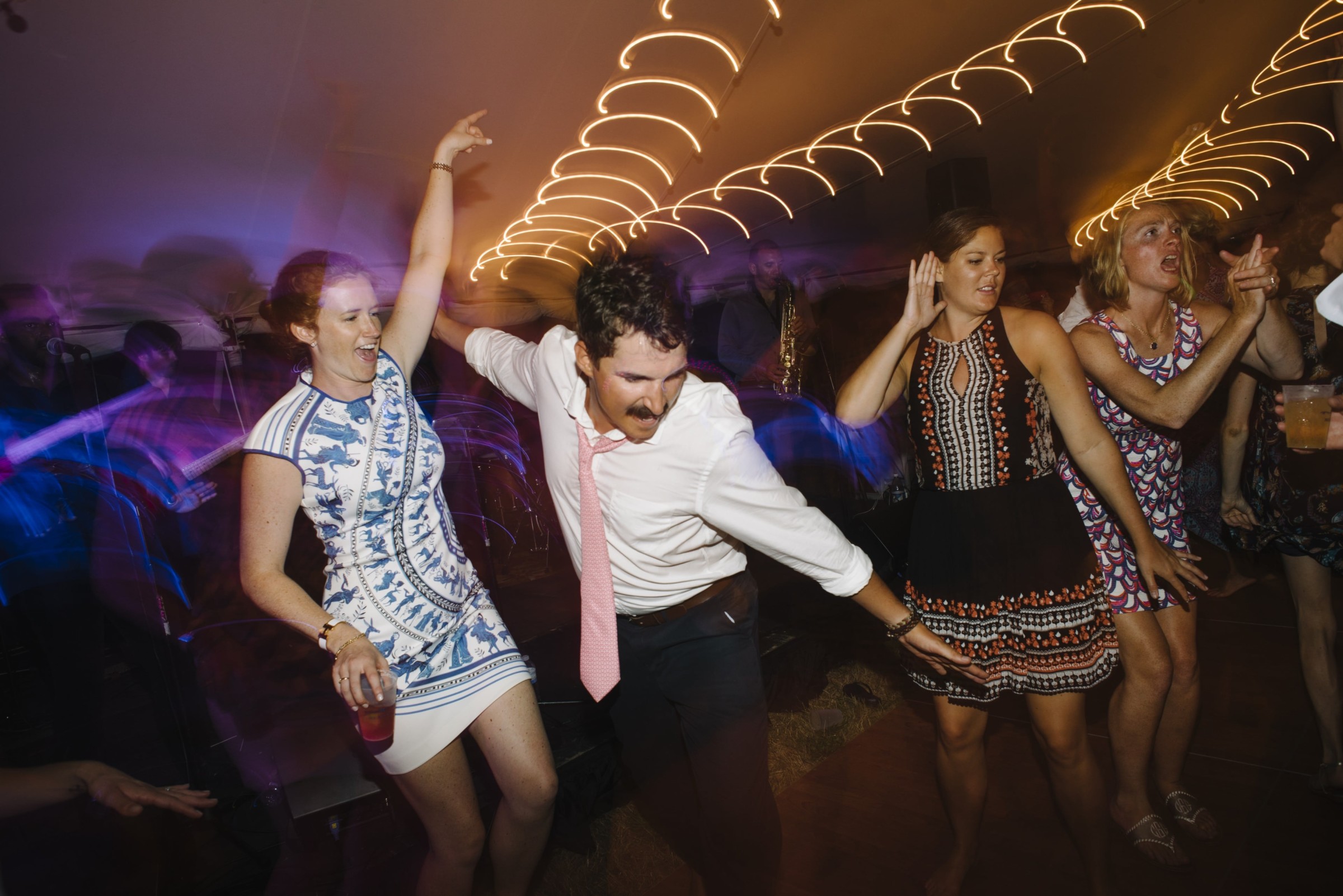 Guests dancing joyfully under string lights at a lively Cuttyhunk Island wedding reception.