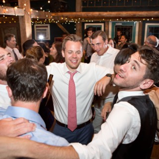 Men celebrating joyfully at a rustic wedding reception in Stone Mountain Arts Center, Brownfield Maine.