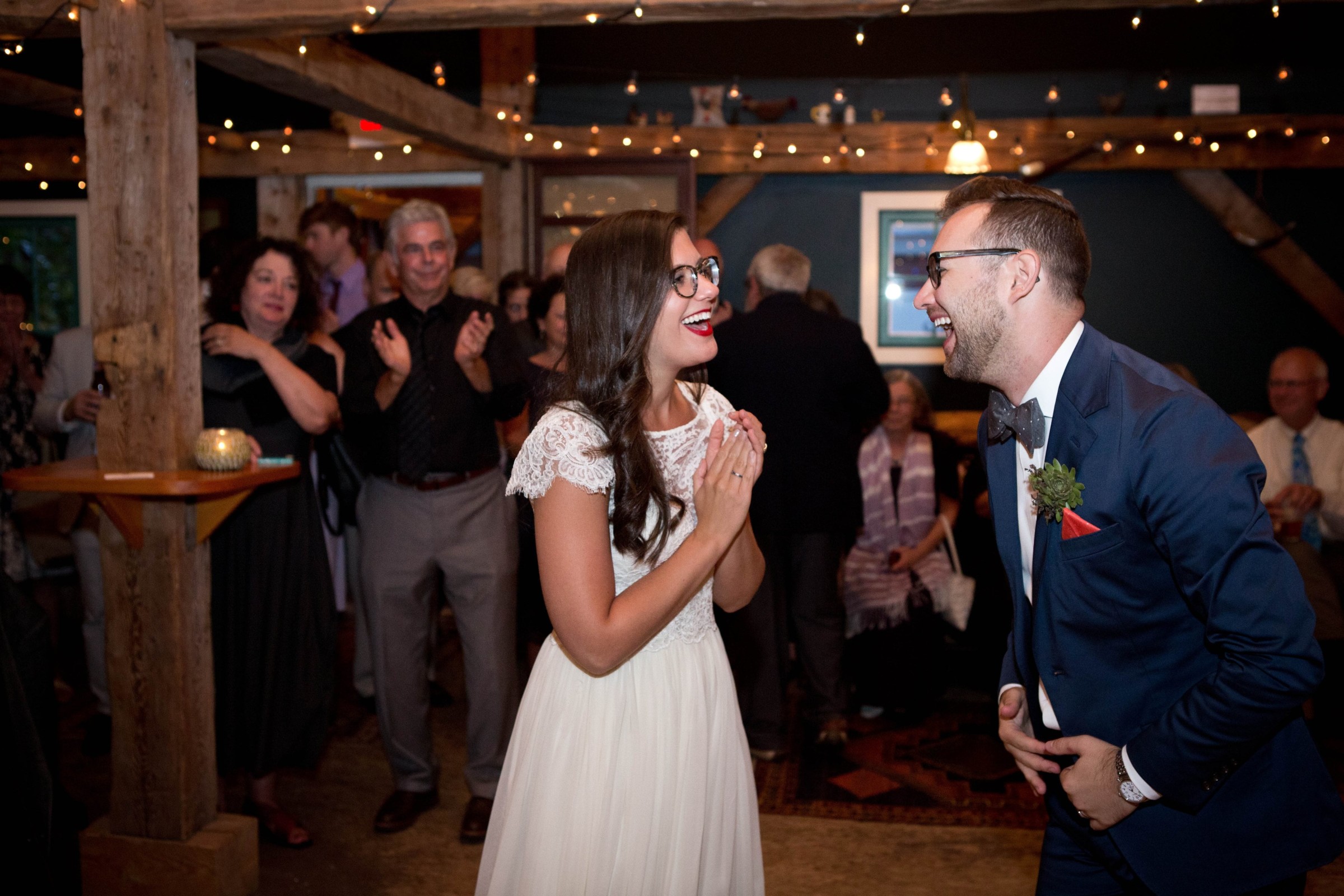 Bride and groom laughing joyfully at rustic wedding reception in Brownfield, Maine.