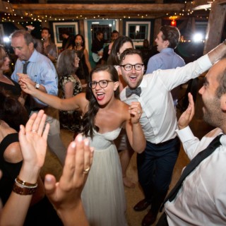 Bride and groom dancing joyfully with guests at rustic Stone Mountain Arts Center wedding.