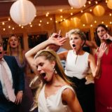 Bride and guests dancing joyfully under warm string lights at Duxbury Bay Maritime School wedding.